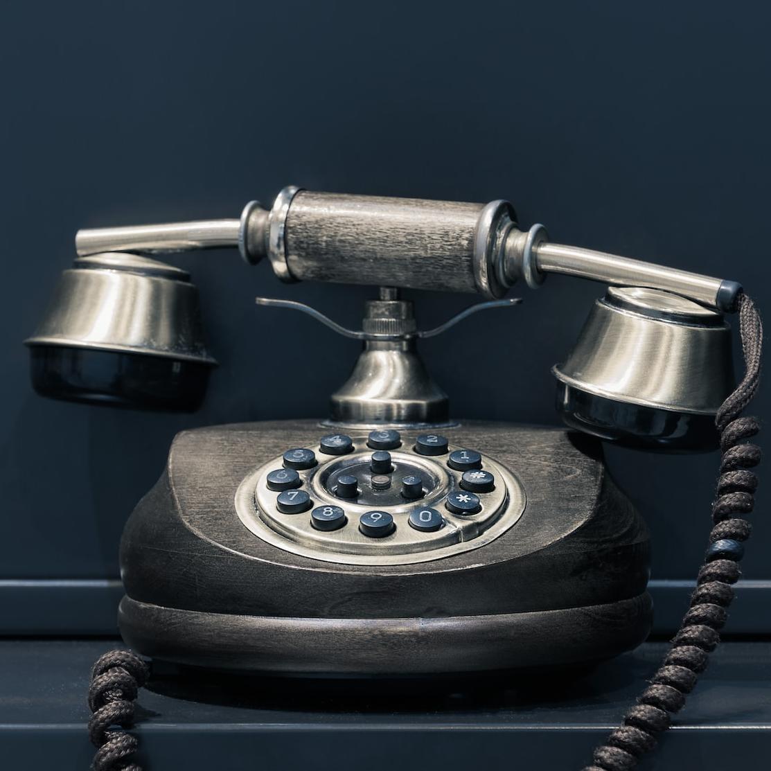 black and brown rotary phone near gray wall